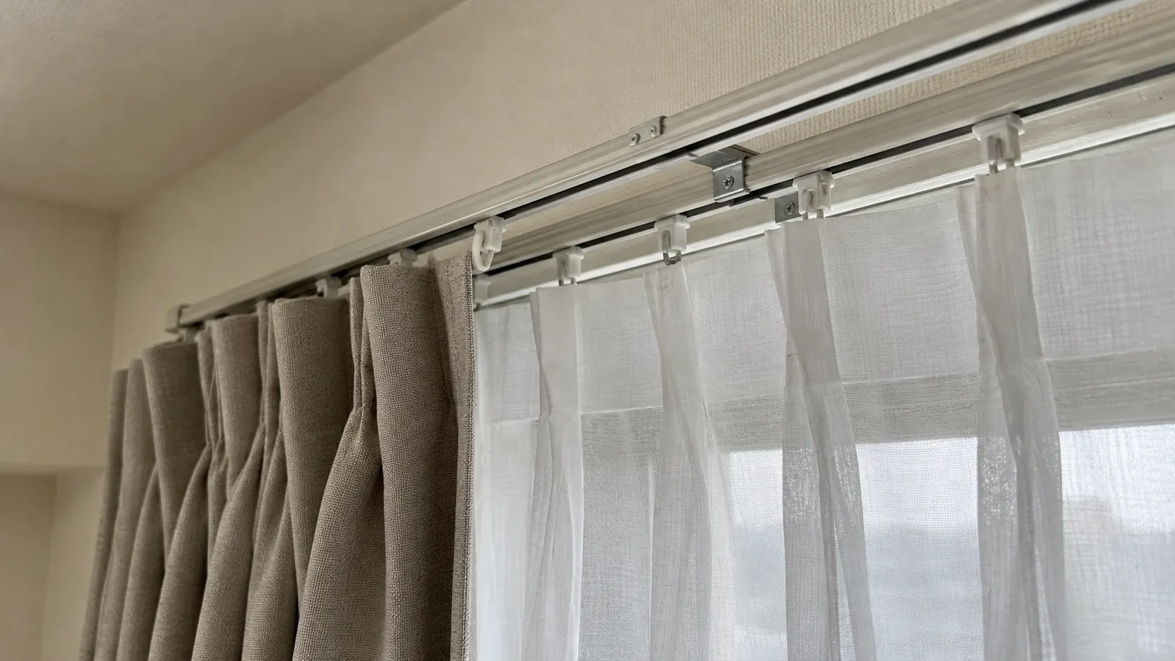 二列のカーテンレールに掛かる厚手の生地と白いレース