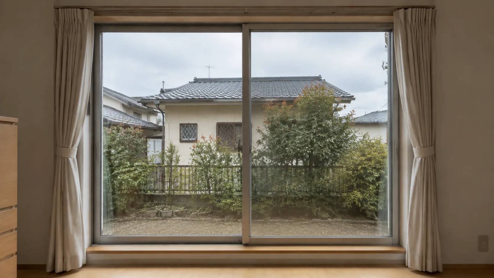 全周をサッシ枠で支持した大きな引き違い窓を室内から見た日本住宅